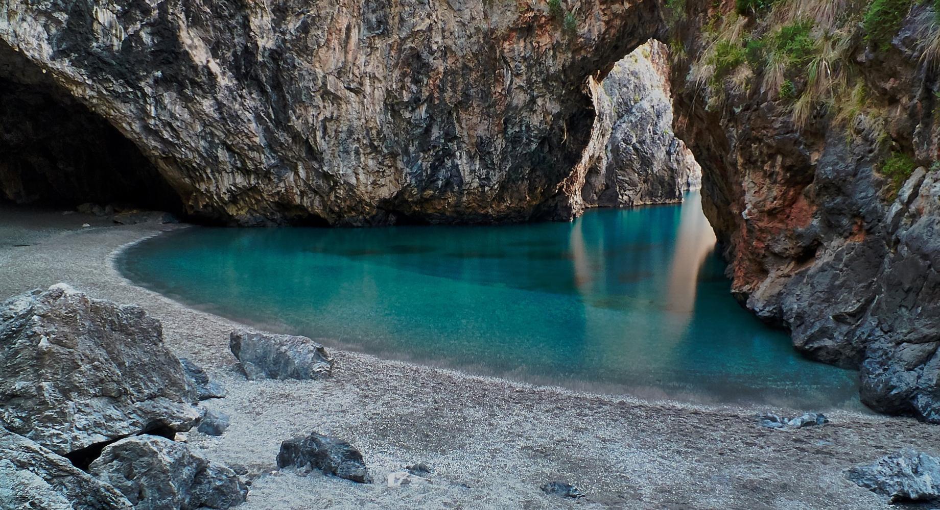 Spiaggia nascosta con acque turchesi e rocce imponenti.