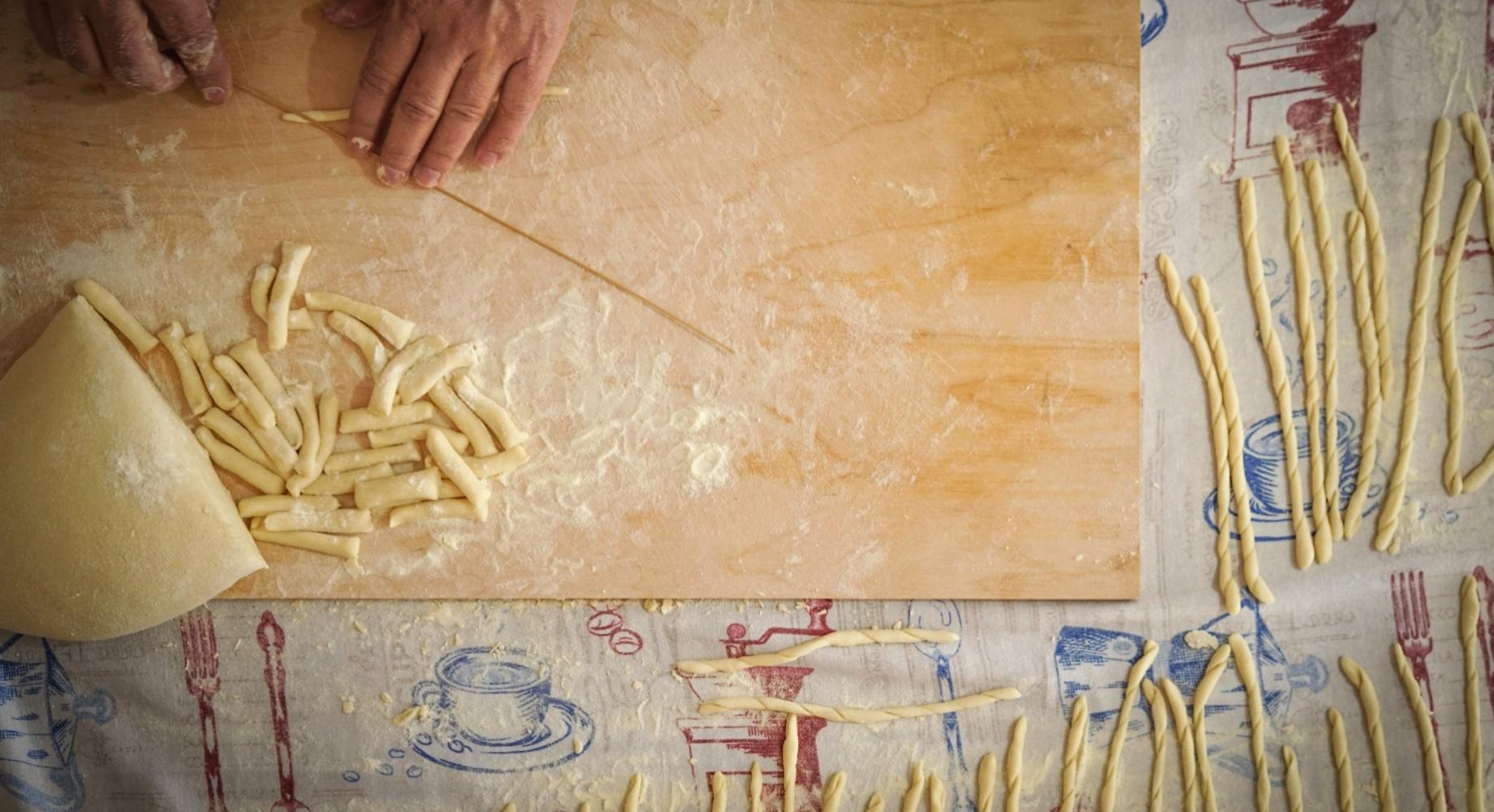 Preparazione di pasta fatta a mano su un tavolo infarinato con un mattarello.