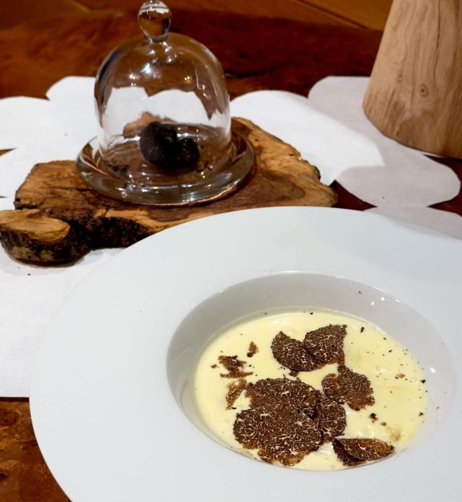 Crema di formaggio con tartufo, servita su piatto elegante, decorazione rustica.